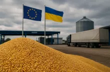 Stos kukurydzy przy granicy UE–Ukraina, w tle flagi i ciężarówka