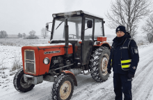Policjant stojący przed czerwonym ursusem