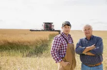 rolnicy stoją na polu, w tle kombajn, koniec lata, żniwa