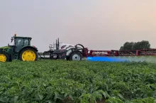 Opryskiwacz producenta Agroma Millenium ET/ST/T przyczepiony do ciagnika podczas pracy w polu