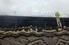 strażak na drabinie gasi dach stodoły w której znajdują się krowy