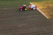 Ciągnik z opryskiwaczem wykonujący oprysk młodej uprawy.
