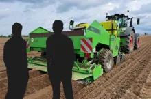dwóch mężczyzn stoi tyłem, patrzy na pole i na ciągnik