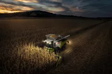 Oświetlony podczas nocnych żniw kombajn Claas Trion 760