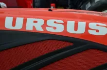 Zbliżenie na maskę ciągnika Ursus – widoczne logo marki na czerwonej obudowie maszyny rolniczej.
