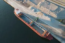 Statek towarowy podczas przeładunku materiału sypkiego w porcie morskim.
