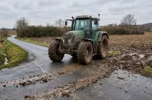 Ciągnik na drodze z błotem rozciągniętym z pola