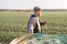 starszy rolnik na polu, na dole banknoty polskie