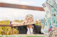 rolnik siedzi i patrzy przed siebie na pole, po prawej banknoty polskie