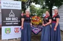 Sołtyska Joanna Nowak (w środku) z koleżankami z koła przy banerze sławiącym historię Giecza i państwa polskiego