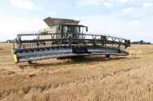 Kombajn zbożowy z hederem na polu podczas żniw