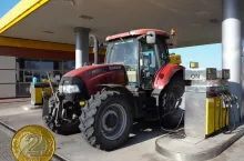 traktor tankujący na stacji paliw, po lewej na dole moneta 2 złote