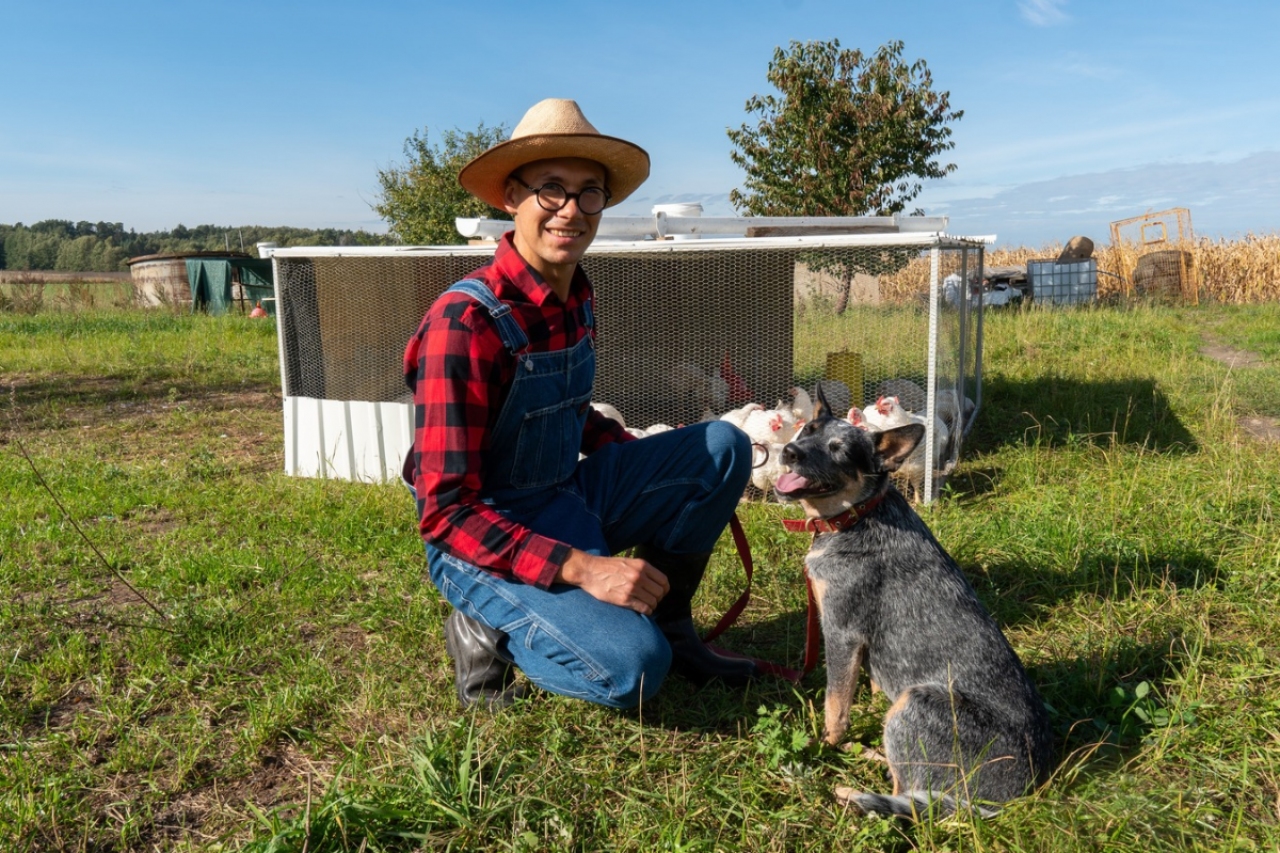 Łukasz Marciniak wraz ze swoim psem Chilli rasy Australian Cattle Dog na pastwisku przy moblinym kurniku